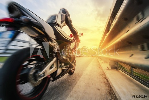 Picture of Moto da strada sfreccia vicino al guard rail al tramonto